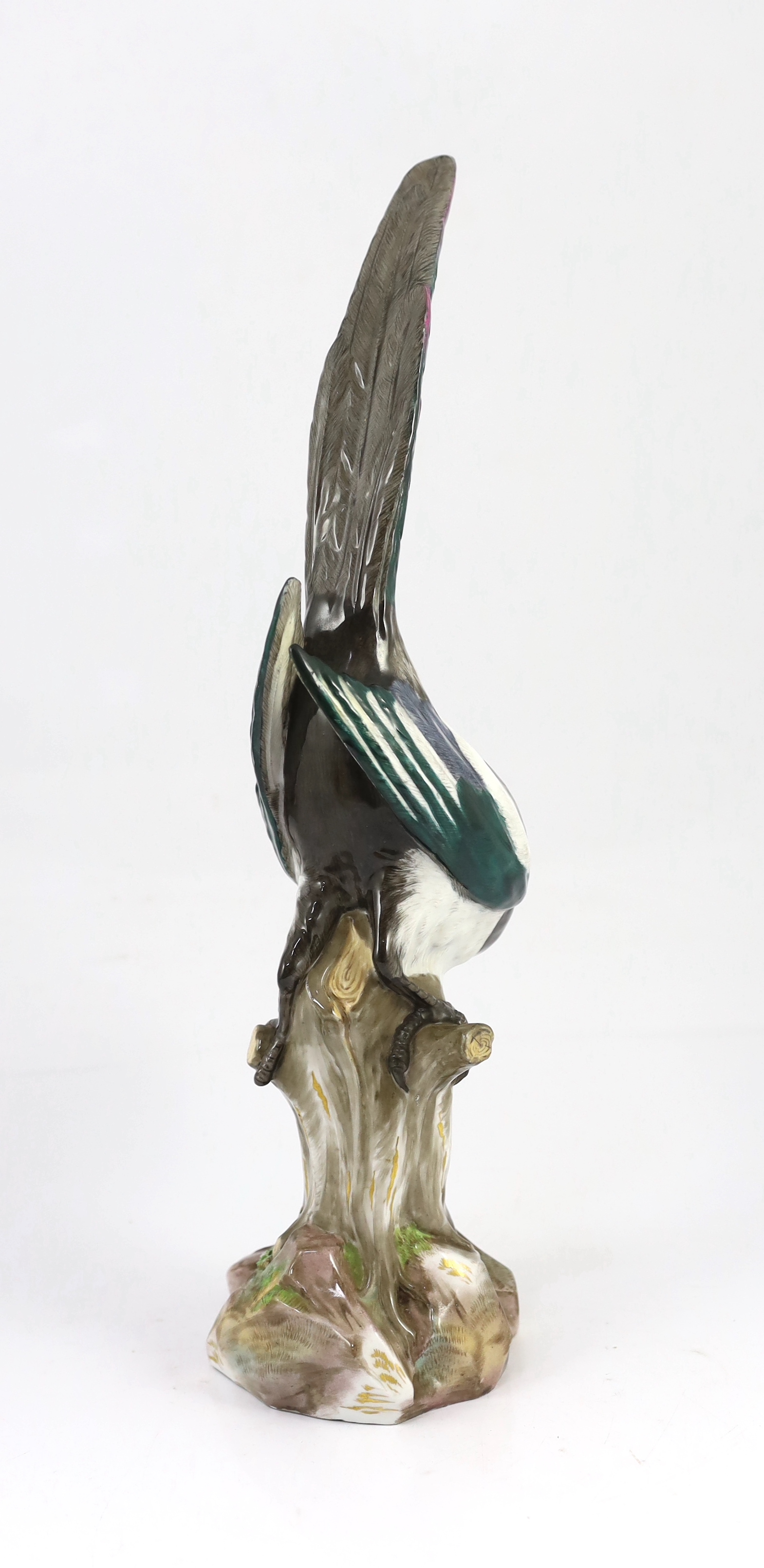 A tall Meissen figure of a magpie, 19th century, perched on a tree stump, incised model no. 62, underglaze blue crossed swords mark, 50cm high, restoration to beak and one wing tip